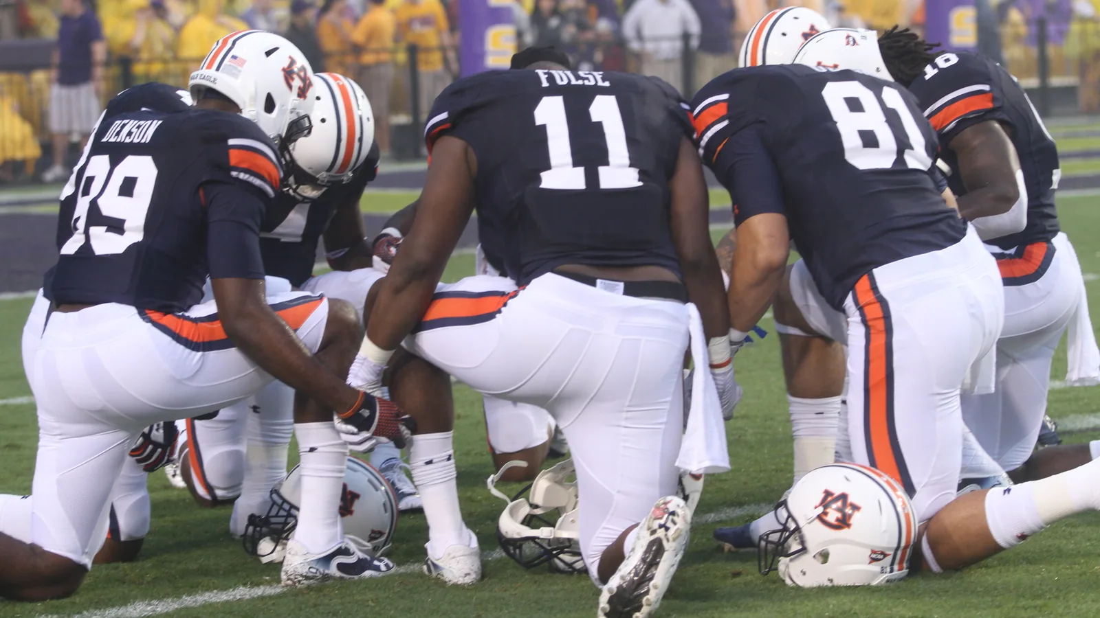 Auburn players kneel together before a game at LSU.