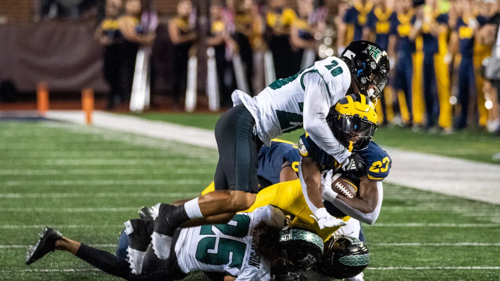 Hawai‘i defenders tackle a Michigan ball carrier during a 2022 game at Michigan Stadium.