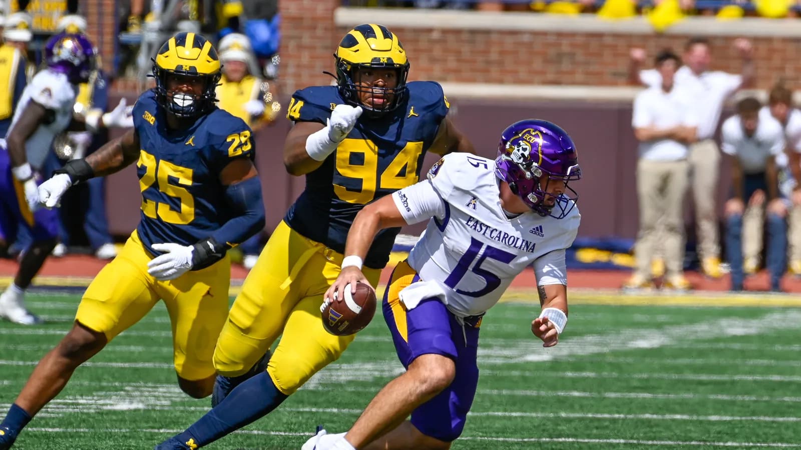 Michigan defenders pursue East Carolina quarterback Alex Flinn at Michigan Stadium in 2023.