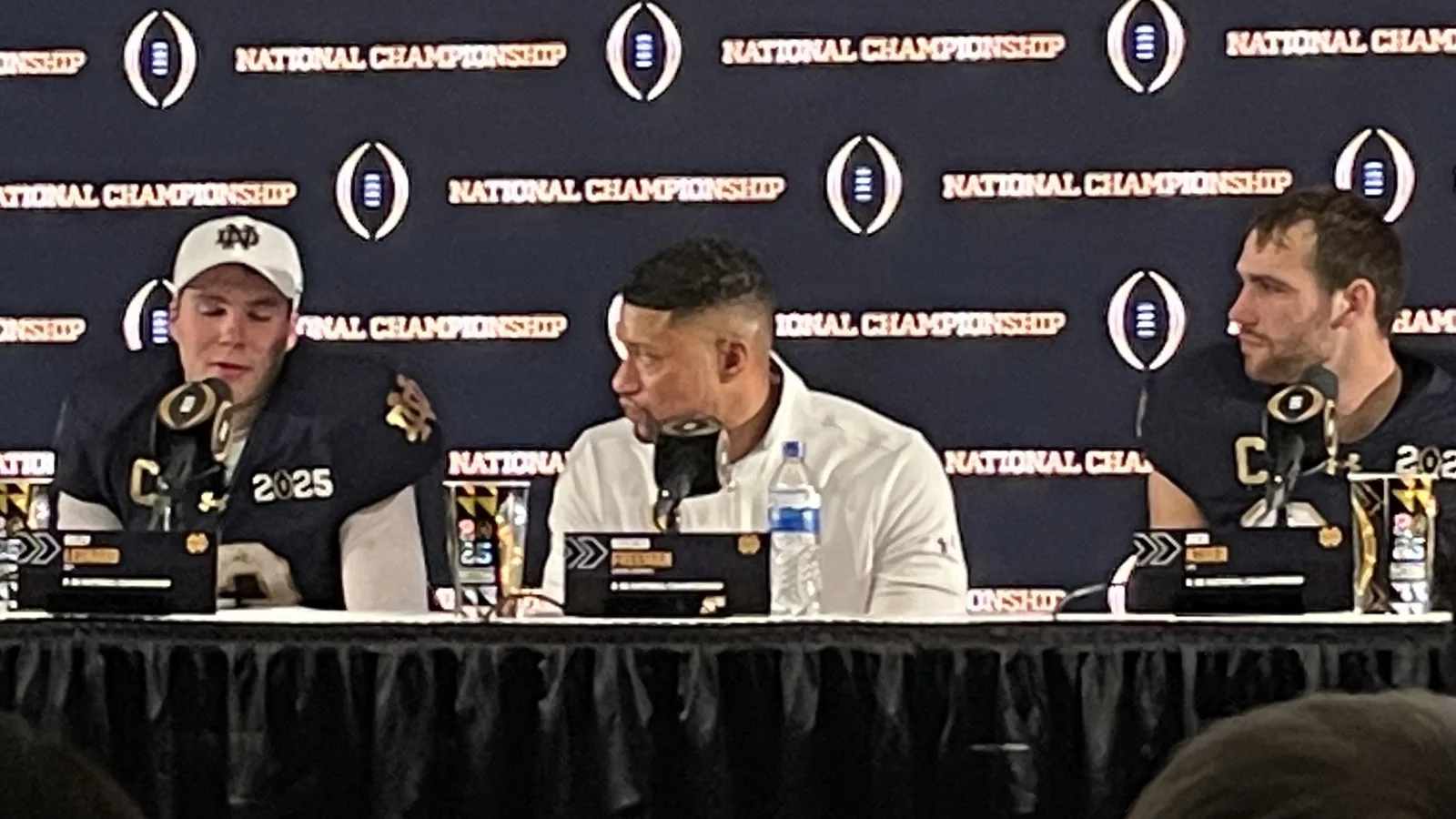 Notre Dame coach Marcus Freeman sits with Riley Leonard and Jack Kiser after a game.