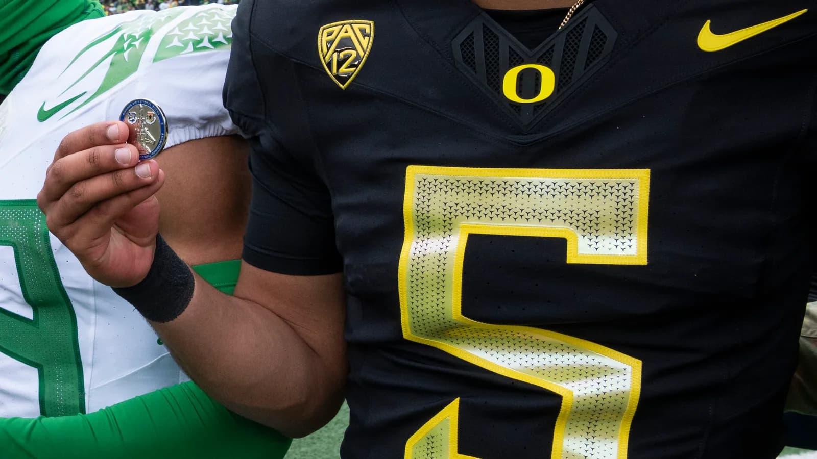 Oregon quarterback Dante Moore holds a challenge coin at Autzen Stadium.