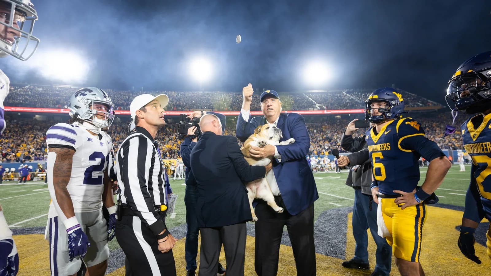West Virginia governor Jim Justice does the coin toss in front of Mountaineers quarterback Garrett Greene
